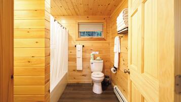Een houten badkamer in een vakantiehuisje, met toilet, raam en handdoekhouder.