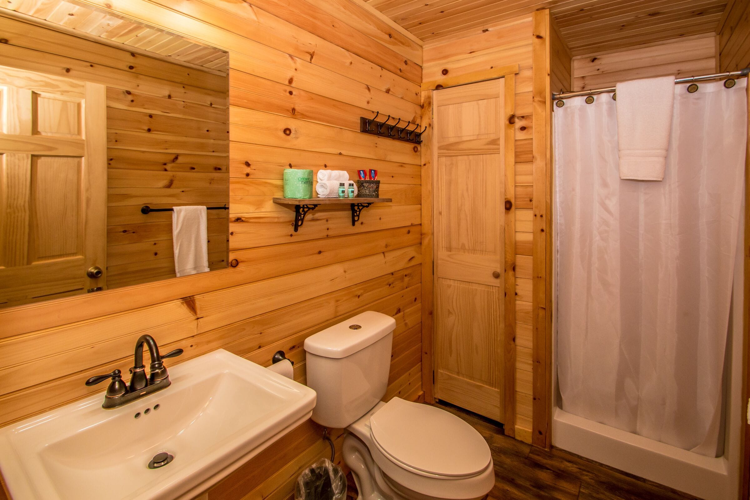Baño de cabaña de madera con lavamanos, inodoro y ducha.