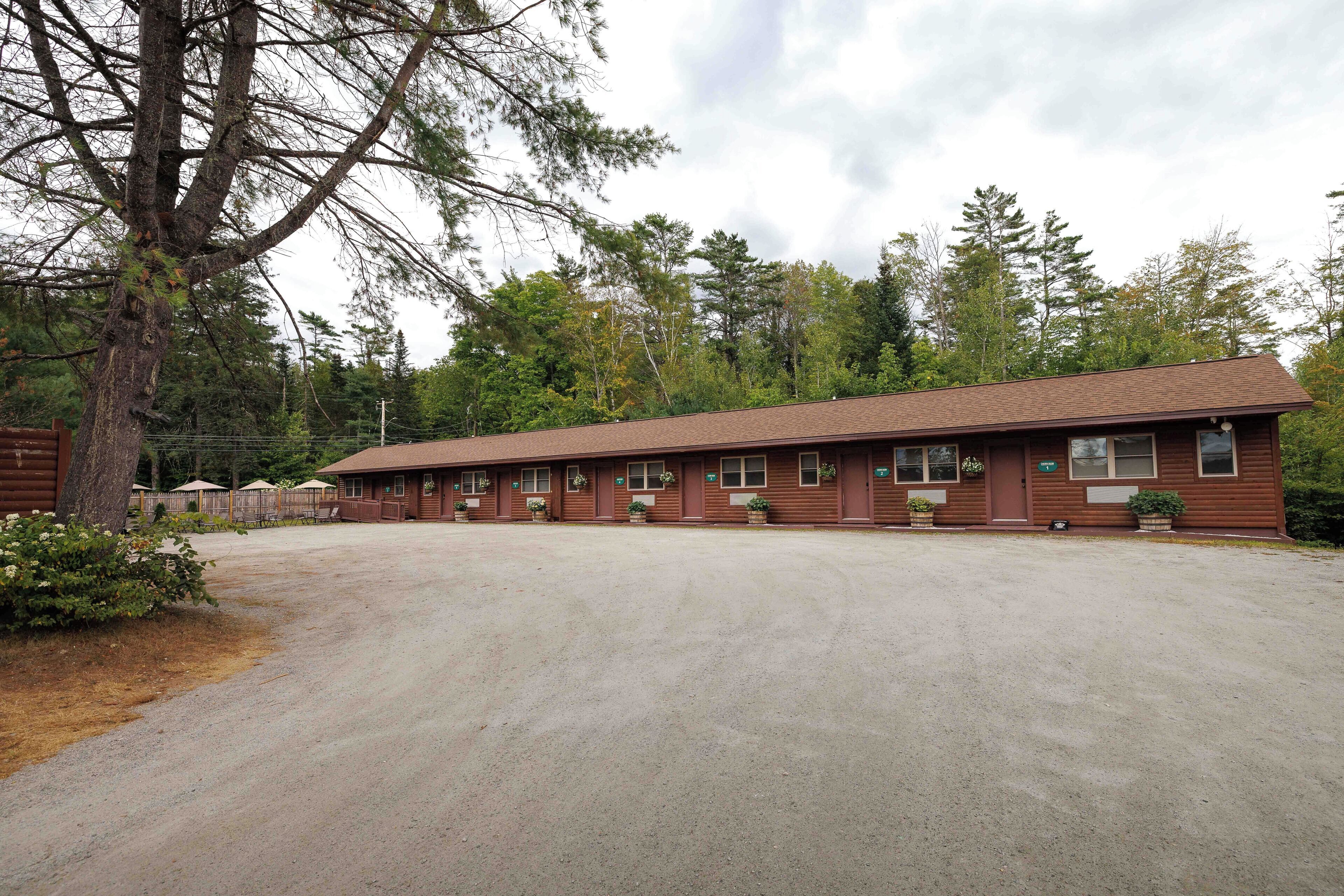 A motel with a long, single-story building, multiple windows, and a gravel parking area.