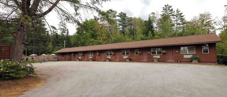 A motel with a long, single-story building, multiple windows, and a gravel parking area.