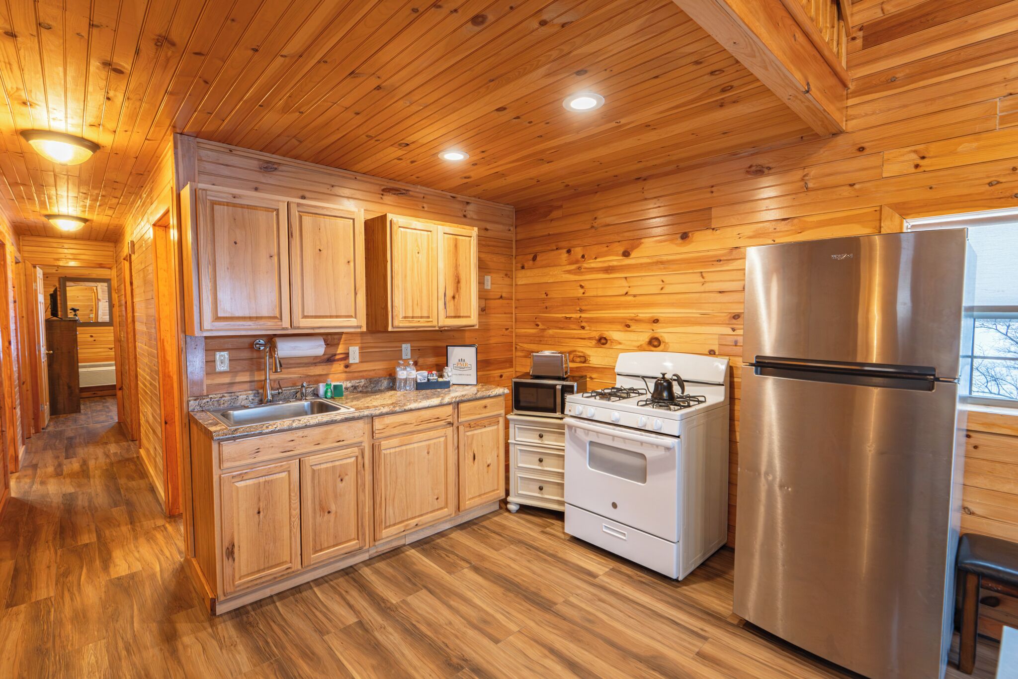 A wooden-paneled kitchen with a stainless steel refrigerator, stove, and microwave.