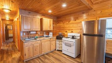 Una cocina con paneles de madera, un refrigerador, un horno y un microondas de acero inoxidable.
