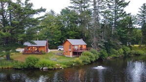 Two wooden cabins by a lake with a dock, surrounded by dense forest. - Presidential Mountain Resort (Bethlehem)