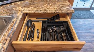 A drawer with kitchen utensils including a spatula, spoon, and knife set.