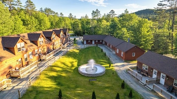 Eine Lodge mit mehreren Blockhütten, einem zentralen Brunnen und einem gepflegten Rasen.