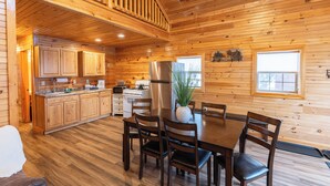 A wooden cabin interior with a dining area, kitchen, and a staircase. - Presidential Mountain Resort (Bethlehem)