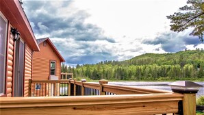 A wooden cabin with a deck overlooking a lake and forested hills. - Presidential Mountain Resort (Bethlehem)