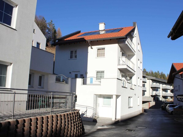 A multi-story residential building with balconies, a gated entrance, and a clear sky. - Apartment in Fiss Near Ski Lifts (Fiss)