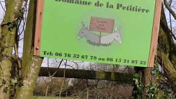 Ein Schild mit französischem Text, umgeben von Bäumen und Farne.