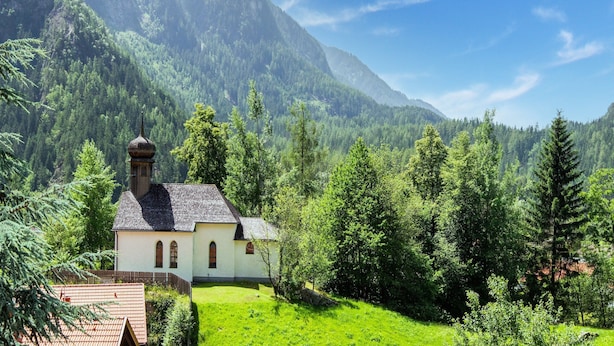 A small white church with a bell tower, surrounded by lush green trees and mountains in the background. - Cozy Holiday Home in Tyrol near Ski Area (Oetz)