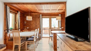 A wooden cabin interior with a dining area, a TV, and a kitchen counter. - Cozy Holiday Home in Tyrol near Ski Area (Oetz)