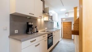 A modern kitchen with white cabinets, stainless steel appliances, and a wooden staircase. - Cozy Holiday Home in Tyrol near Ski Area (Oetz)