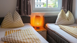 Habitació d'hotel amb dos llits, una petita taula de nit amb una làmpada i cortines amb dibuixos de cérvols.