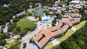 Eine Vogelperspektive eines Resorts mit Swimmingpool, Tennisplätzen und einem großen Gebäude mit rotem Dach.