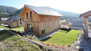 A wooden cabin with a sloped roof, a small deck, and a view of the surrounding mountains. - Lavish Wooded Chalet with Sauna & Hot Tub in Hohentauern (Hohentauern)