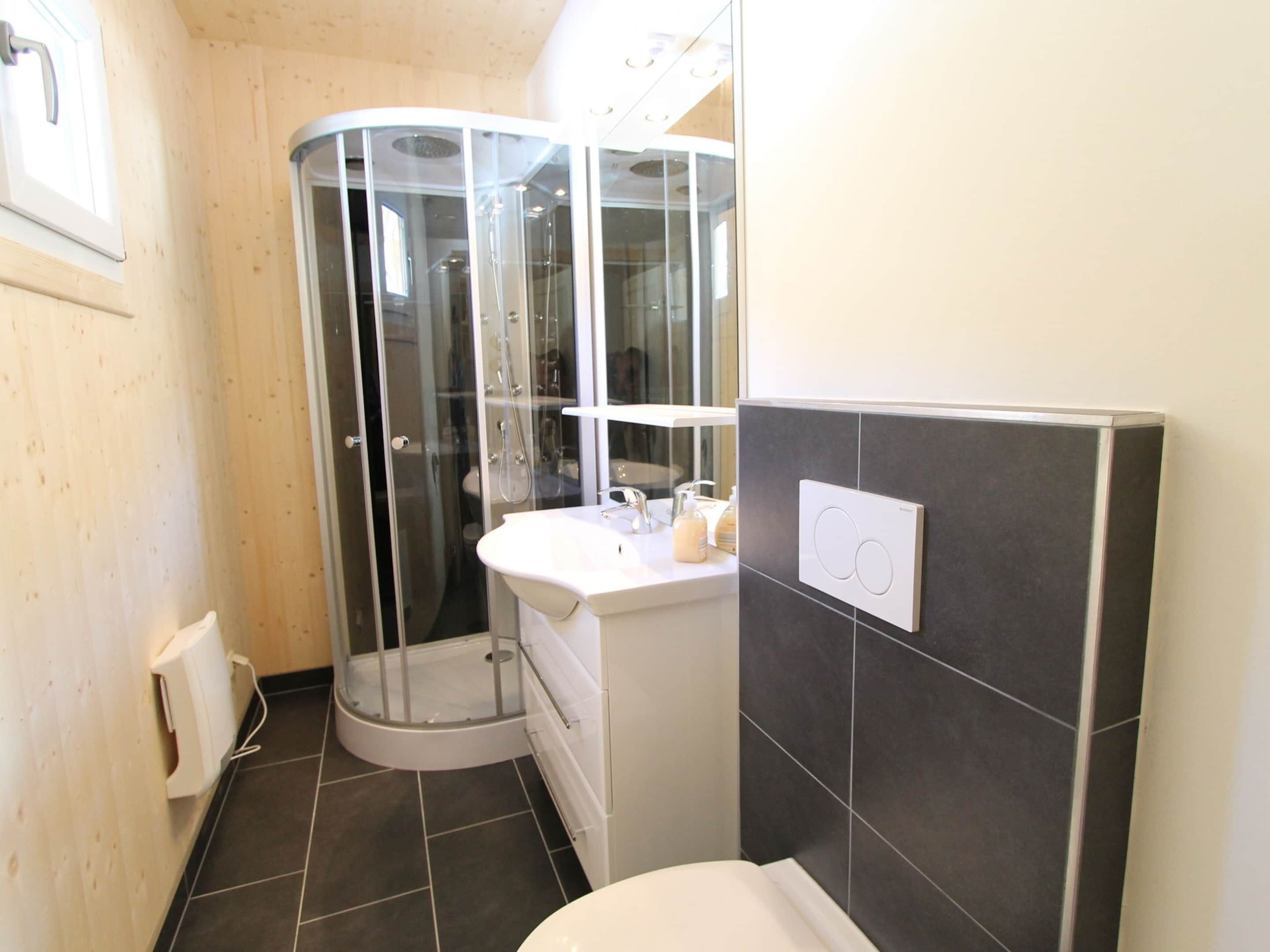 A modern bathroom with a glass shower enclosure, a white sink, and a toilet.