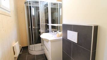 A modern bathroom with a glass shower enclosure, a white sink, and a toilet.