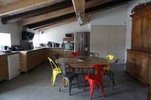 Eine Küche mit Holzschränken, einem Esstisch mit Stühlen und einem Einbauofen.