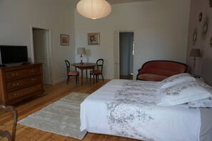 Ein Schlafzimmer mit einem Bett, einem Schminktisch, einem Schreibtisch mit Stühlen und einer Pendelleuchte.