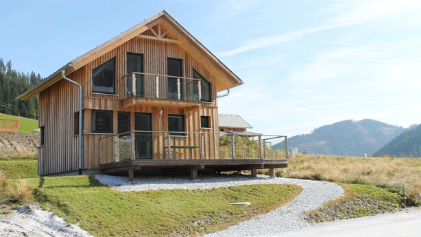A wooden multi-story house with a balcony, a gravel driveway, and a mountainous backdrop. - Chalet in Hohentauern Near Ski Lift (Hohentauern)