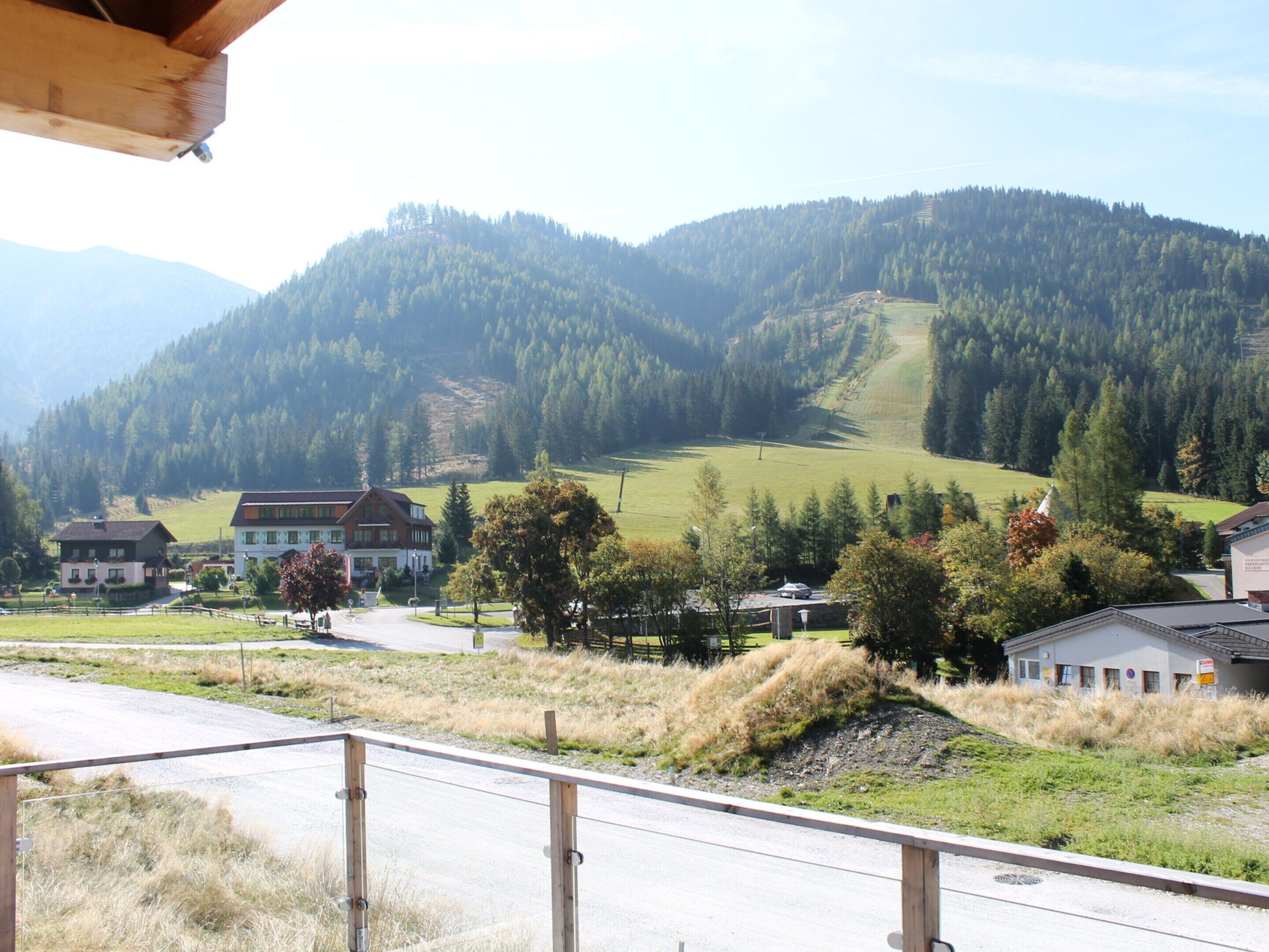 A rural landscape with a road, a few buildings, and a mountainous backdrop.
