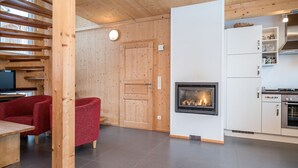 A modern interior with a fireplace, wooden walls, a dining area, and a kitchen. - Chalet in Hohentauern Near Ski Lift (Hohentauern)