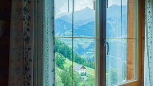 A room with a large window offering a view of a green valley and mountains. - Cozy Apartment in Fendels near Ski Area (Fendels)