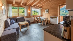 A cozy wooden cabin with a living area featuring a sofa, a table, and a dining set. - Cozy Apartment in Fendels near Ski Area (Fendels)