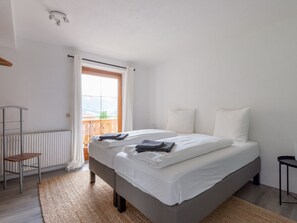 A bedroom with a large bed, a radiator, a wooden chair, and a view of the outdoors through a window. - Beautiful Holiday Home Near St Anton Am Arlberg With Sauna (Pettneu am Arlberg)