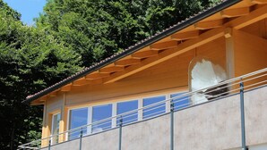 Un edificio moderno con balcón, ventanas grandes y techo de madera.