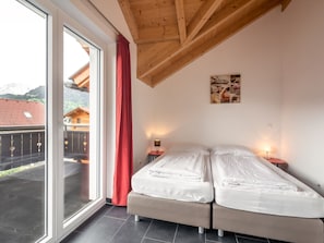 A bedroom with two beds, a large window, and a wooden ceiling. - Spacious Chalet in Kötschach-Mauthen near Ski Area (Kotschach-Mauthen)