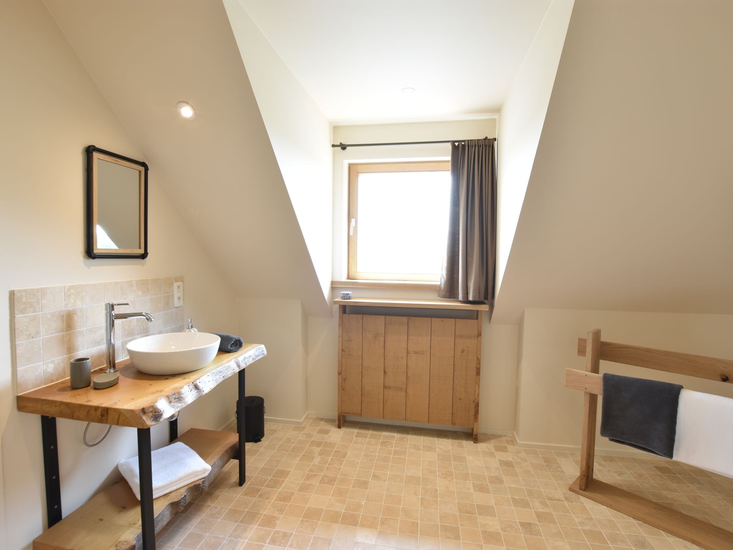 Une salle de bain moderne dotée d’un puits de lumière, d’un meuble-lavabo en bois, d’une baignoire et d’un grand miroir.