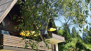 A modern house with a sloped roof, wooden balcony, and a yellow umbrella.