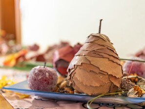 A pear-shaped object with a textured surface, possibly made of wood or leather, placed on a blue plate with other food items.
