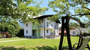 A residential building with a balcony, a swing set, and a grassy yard. - Country House in Koetschach-mauthen in ski Area (Kotschach-Mauthen)