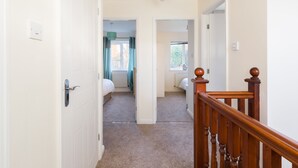 A hallway with a wooden staircase leading to a bedroom with a window.