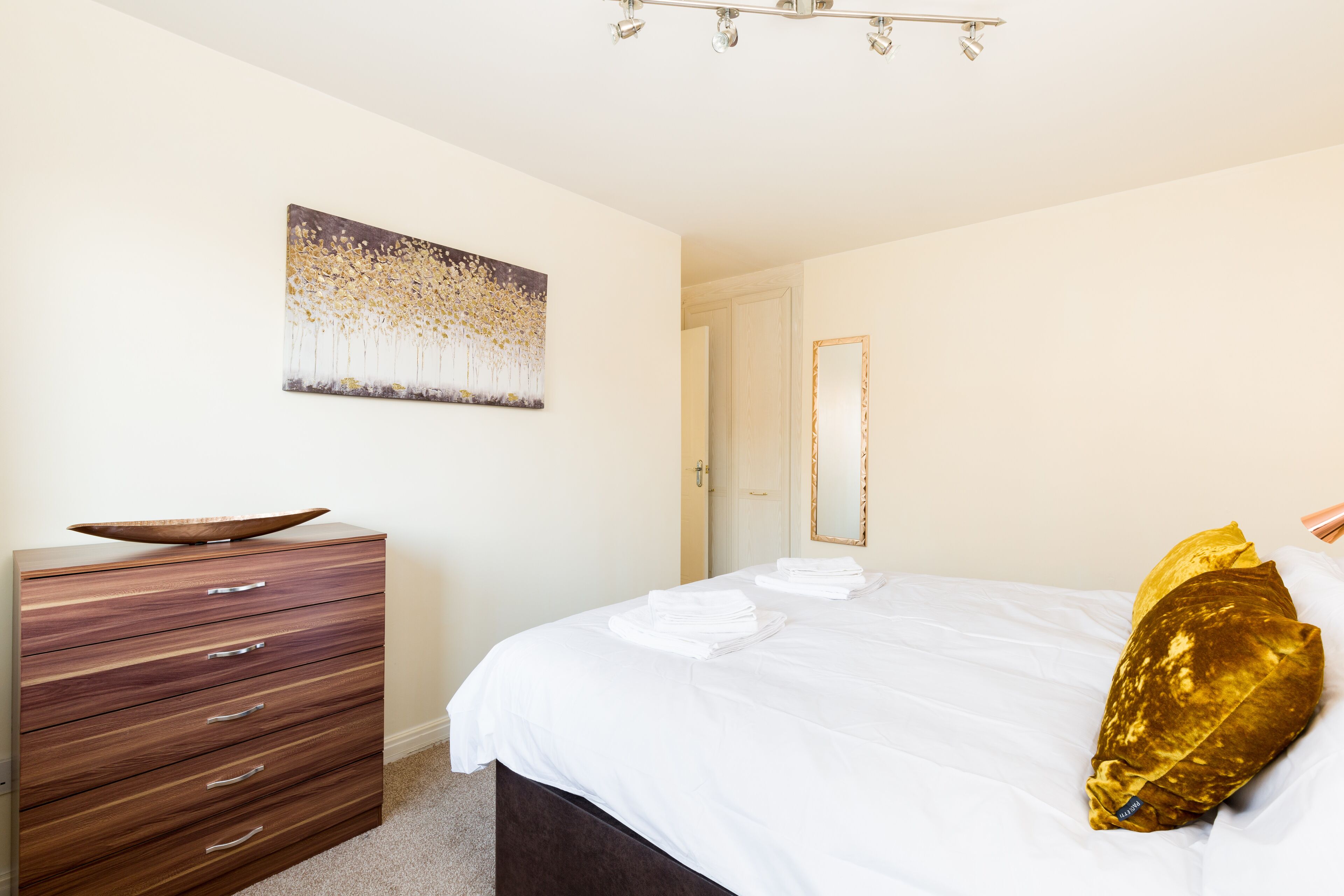 Un dormitorio con cama, cómoda, cuadro y puerta.