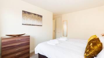 Un dormitorio con cama, cómoda, cuadro y puerta.