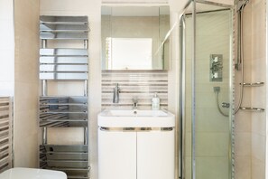 A modern bathroom with a glass shower enclosure, a stainless steel towel rack, and a white sink with a mirror above it.