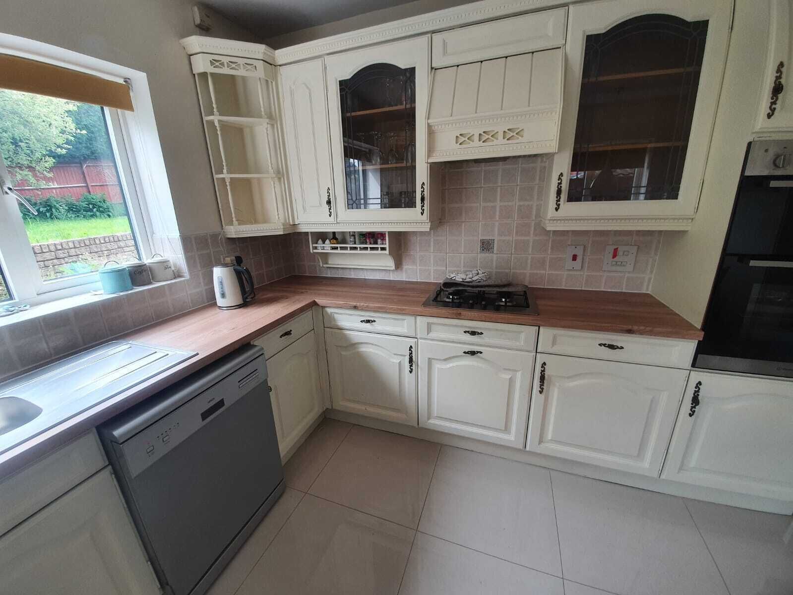 A kitchen with white cabinets, a wooden countertop, and a dishwasher.