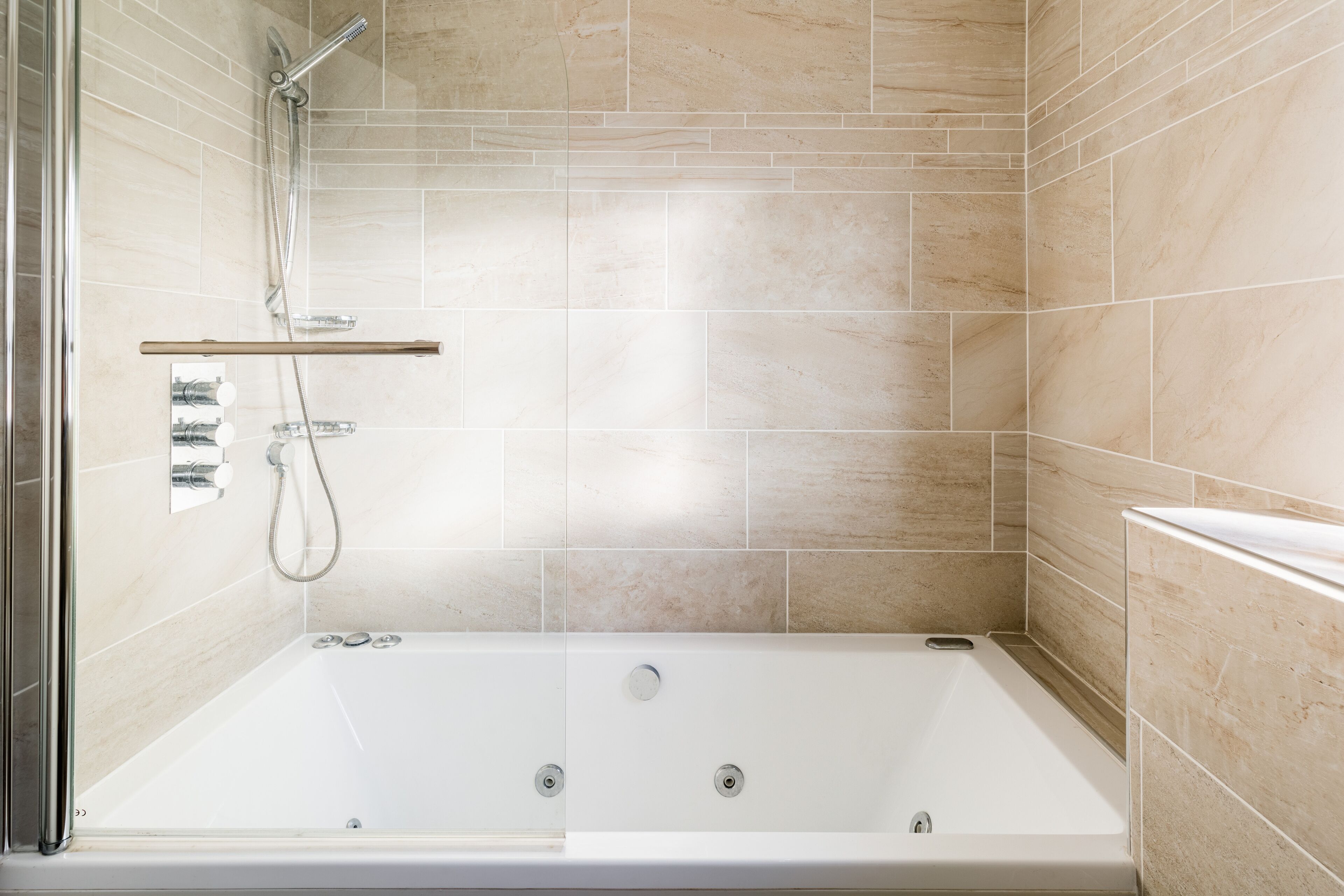 Un baño moderno con ducha a nivel del suelo, bañera y zona de ducha con mampara de vidrio.