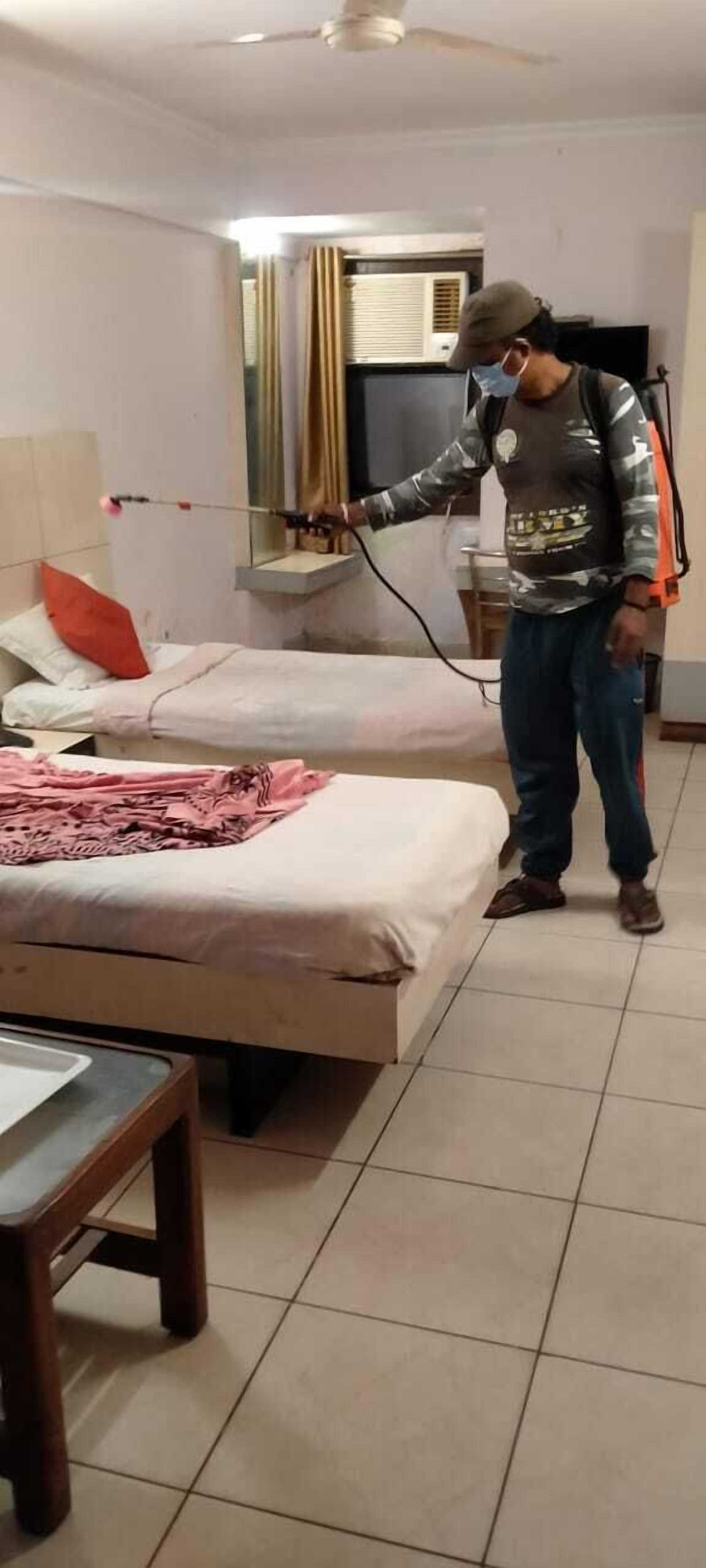 A room with two beds, a wooden table, and a ceiling fan.