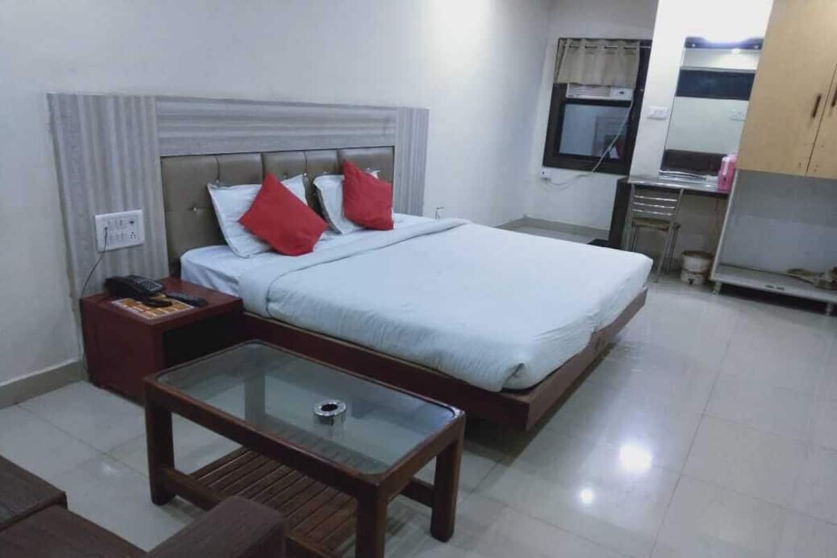 A neatly arranged hotel room with a bed, bedside table, and a small glass-top table.