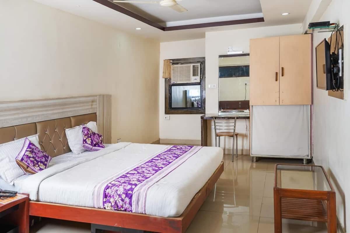 A hotel room with a bed, a desk, and a wardrobe.