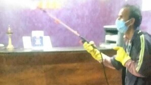 A person using a spray device in a room with a purple wall and a wooden counter. - Lals Plaza Hotel (Bhopal)
