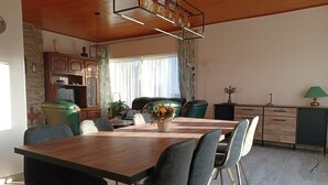 A dining area with a wooden table, black chairs, a green sofa, and a kitchen area with cabinets and a countertop. - A Villa Between the Town Centre and the Forest (Spa)