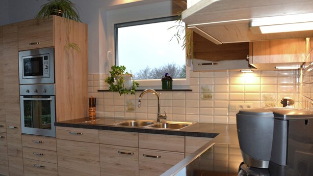 A modern kitchen with wooden cabinets, stainless steel appliances, a window with a view, and a coffee maker. - A Villa Between the Town Centre and the Forest (Spa)