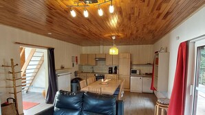 Eine moderne Küche mit Holzschränken, einem Esstisch und einem schwarzen Ledersofa.