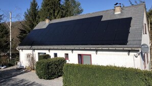 Ein Haus mit einem geneigten Dach, das mit Solarmodulen bedeckt ist.