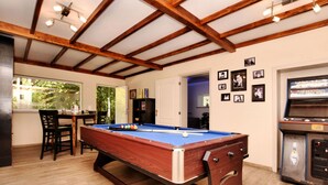 Ein Billardtisch in einem Raum mit Holzbalkendecke, ein Billiardtisch und eine Kegelbahn.